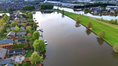 Etrafı yemyeşil ve kanallarla çevrili köyün hoş manzarası. Vinkeveen Panoraması, Hollanda Alacakaranlık vakti.