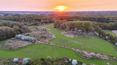 Parktaki çayır yemyeşil ormanlarla çevrili. Gün batımında kırsal bölgede hava perspektifi.