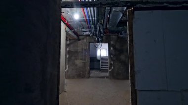 Binanın rekonstrüksiyon altındaki koridorunun yanından geçiyor. Merdivenlere yaklaşan çıplak duvarlarla odaları dolaş..