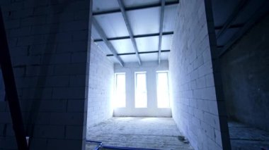 Odaya beyaz tuğlalı duvarlar ve üç büyük pencereyle giriyorlar. Bir bina inşa etmek.