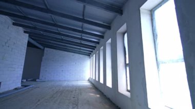 Geniş, geniş pencereli bir oda. Beyaz tuğla duvarlar ve binanın yeni çatısı..