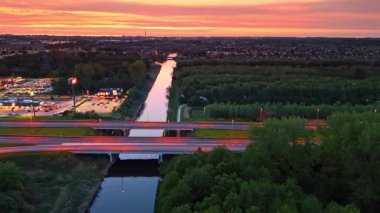 Hollanda 'da günbatımı kanalı. Gün batımının ışıltısı gökyüzünü bir kanal ve otobanın üzerinde aydınlatıyor, alacakaranlıkta Hollanda 'nın güzelliğini gösteriyor..