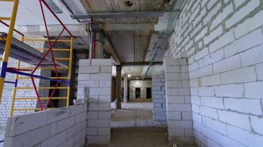 Yeni inşaat salonu tadilatta. Açığa çıkmış duvarları ve iskelesi olan, ilerleme ve yapıyı gösteren bitmemiş bir inşaat alanının iç görünümü.
