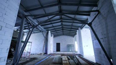 Çelik kirişlerin iç manzarası. Çelik kirişler ve tamamlanmamış duvarların yer aldığı geniş bir inşaat alanı..