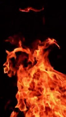 Sıcak kırmızı alev havada yatay ve dikey olarak yükseliyor. Karanlıkta dans eden güzel bir alev. Dikey video