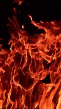 Büyük şenlik ateşi ve uçan ışıklar. Tahta çubuklar gece kamp ateşinde yanar. Dikey video