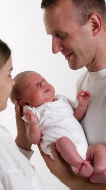 Yeni doğmuş bebeğini kucağında tutan mutlu adam. Sevgi dolu anne, sevgili çocuğuna yaslanır. Beyaz zemin. Dikey video