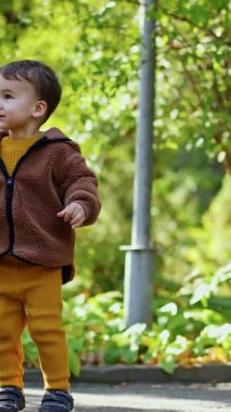 Güzel beyaz çocuk sabun köpüklerini yakalıyor. Güzel bebek sonbaharda dışarıda eğleniyor. Dikey video