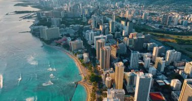 Dalgalar lüks Waikiki plajına yuvarlanıyor. Gün batımında güzel bir tatil köyüne havadan bakış açısı, zaman.