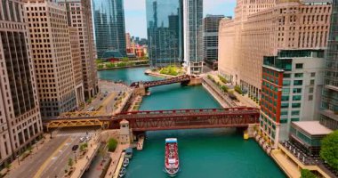 Turistli tekne Chicago Nehri 'nin kıyısında köprülerin altında yüzüyor. Manzaranın etrafındaki güzel binalar.
