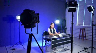 Bir video stüdyosu yaratıyorum. Bir içerik yaratıcısı, iyi aydınlatılmış bir stüdyoda birden fazla kamera ve ışıklandırma ayarlarıyla bir kayıt oturumuna hazırlanıyor..