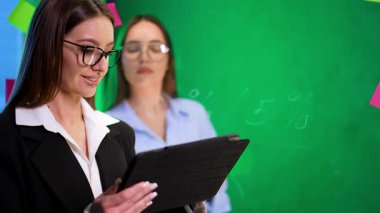 İki işçi iş başında. Gözlüklü bir kadın tablet kullanırken, diğeri gün boyunca parlak ve renkli bir ofis odasında gözlem yapıyor..