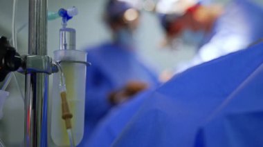 Ameliyathanede cerrahi prosedür. Mavi önlüklü tıp uzmanları steril bir ortamda hasta bakımı ve hassasiyetine odaklanarak ameliyat yapıyorlar..