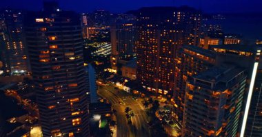Canlı kentteki iyi ışıklandırılmış yolun üzerinden uçmak. Waikiki, Honolulu, Hawaii, ABD 'deki binaların tepesindeki İHA görüntüleri..