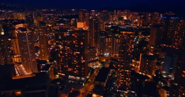 Modern Honolulu 'nun gece manzarası, Hawaii, ABD. Işıkları açık olan binaların tepesindeki İHA görüntüleri..