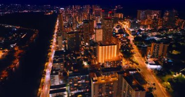 Olağanüstü aydınlatılmış modern Waikiki, Honolulu, Hawaii, ABD. İHA görüntüleri gece manzaranın üstünde. Ala Wai Kanalı ve Pasifik Okyanusu 'nun karanlık bölgeleri..