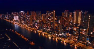 Işıklar, Honolulu, Hawaii, ABD 'den Waikiki' yi özetleyen Ala Wai Kanalı 'nın karanlık sularını yansıtıyor. Şehrin göz kamaştırıcı bir manzarası var..