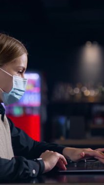 Maskeli karantina çalışanı portresi. Maskeli güzel bayan bilgisayarla çalışıyor. Dikey video