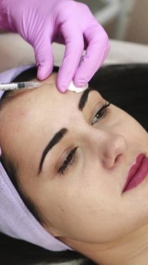 Bir kozmetoloji kliniğinde iğne işlemi yapan bir kadın.