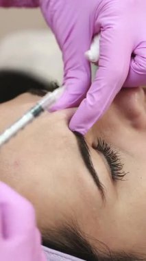 Fizyoterapi prosedürü, kozmetik bilimi. Güzellik uzmanı kadınlar için yaşlanmaya karşı iğne yapıyor. Cilt bakımı. Dikey video