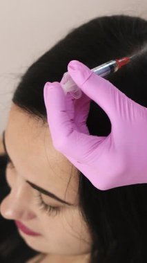 İğne mezoterapisi. Kozmetik uzmanı kadın kafasına enjeksiyon yapıyor. Saçı güçlendir ve büyümelerini dikey görüntüle