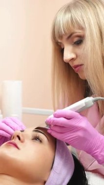 Doktor-kozmetik uzmanı kozmetoloji salonunda ultrasonik temizlik yapıyor. Estetik kozmetoloji. Dikey video