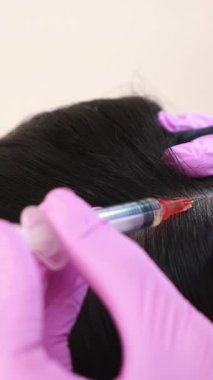 Güzel genç bir kadın estetik ilacın merkezinde kafasına bir iğne vurulur. Saç büyümesini önleme ve tedavi Dikey video