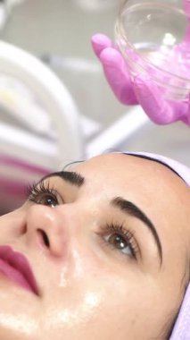 Güzellik uzmanı kaplıcada kadının yüzünü soyuyor. Yüze estetik operasyon. Cilt bakımı dikey video kavramı