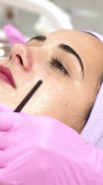 Güzellik uzmanı kaplıcada kadının yüzünü soyuyor. Yüze estetik operasyon. Cilt bakımı dikey video kavramı