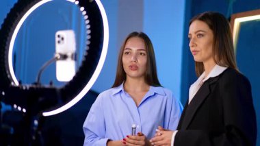 Bir çift bayan kameranın önünde konuşuyor. Kadınlar halka ışığı kullanan bir blog için video kaydediyor.