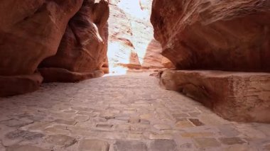 Kum taşı kayaları arasında antik asfalt yol. Petra, Güney Ürdün, Batı Asya 'daki Al Siq Kanyonu' nun alçak açılı görüntüsü.