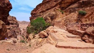 Sıcak ve güneşli bir günde insanlar kayalıklar boyunca gider. Gezginler Petra, Ürdün, Batı Asya 'ya yürüyor.
