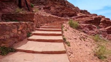 Kırmızı kayalıklarda merdivenlerden yükseliyor. Düşük açılı bakış açısı Petra, Ürdün, Batı Asya kanyonu.