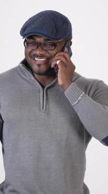 Akıllı telefondan konuşan Afrikalı bir adam. Akıllı telefondan konuşan Afrikalı genç adam gri arka planda izole edilmiş.