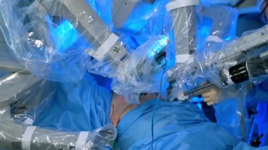 Hasta robot cerrah tarafından ameliyat ediliyor. Tanınmayan doktorun eldivenli eli bir alet tutuyor..