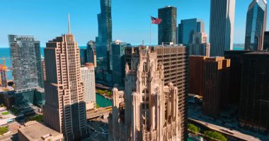 Tribune Kulesi 'nin neo-gotik binasına yaklaşıyoruz. Üzerinde Amerikan bayrağı var. Chicago, Illinois, ABD 'deki diğer gökdelenlerin manzarasını gözler önüne seriyor..