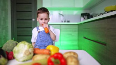 Havuç yiyen sevimli çocuk sebzelerin çeşitliliğine bakıyor. Canlı bebek başka bir havuç seçiyor. Sağlıklı yaşam tarzı.