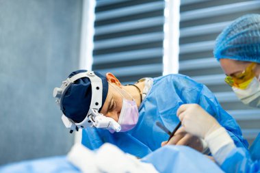 Yüksek teknolojili ameliyathanede cerrahlar. Cerrahi ekip gün boyunca temiz ve iyi aydınlatılmış bir ameliyathanede karmaşık prosedürlere odaklandı..