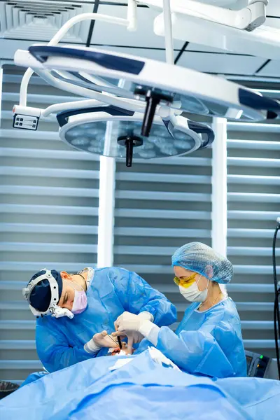 Cerrahlar steril bölgelerde ameliyat yaparlar. Mavi önlüklü iki cerrah, modern bir ameliyathanede cerrahi müdahale sırasında bir hastaya odaklanır..