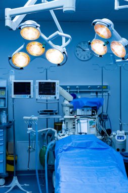 Parlak cerrahi odası düzeneği. Modern bir cerrahi odasında, yaklaşan bir prosedür için hazırlanmış gelişmiş ışıklar ve tıbbi ekipmanlar yer alıyor..