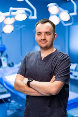 Cerrah pırıl pırıl ameliyathanede parlıyor. Kendine güvenen bir cerrah kollarını kavuşturup uzmanlığını iyi donanımlı bir ameliyathanede gösterir..