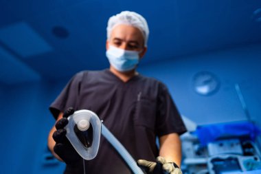 Cerrah anestezi teçhizatını hazırlıyor. Cerrahideki bir sağlık uzmanı steril bir ameliyathanede anestezi aletleri hazırlıyor ve hastanın güvenliğini sağlıyor..