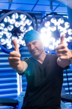 Cerrah ameliyathanede seviniyor. Bir cerrah başarılı bir ameliyattan sonra parlak bir ameliyathanede iki kez onay verir..