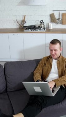 Modern evde çalışan ve oturan çekici bir adam. Karantinada çalışan mutlu, utangaç adam. Dikey video