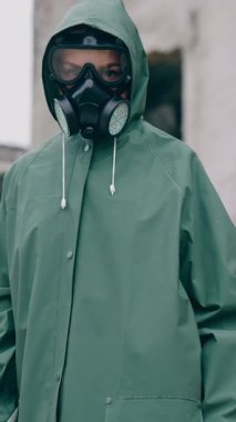 Radyoaktif yeşil takım elbiseli ve gaz maskeli bir insan. Tehlikeli madde giysisi ve eldiven giyen adam. Dikey video