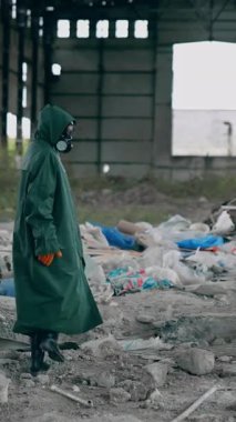 Koruyucu maskeli ve takım elbiseli adam. Biyolojik tehlike üniformalı bir insan boş bir şehirde duruyor. Dikey video