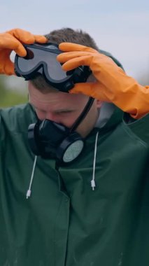 Yeşil kimyasal elbise ve gaz maskesi takan adam. Özel radyoaktif üniformalı bir adam geliyor. Dikey video