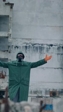 Biyolojik tehlike üniformalı bir insan boş bir şehirde duruyor. Koruyucu maskeli ve takım elbiseli adam. Dikey video