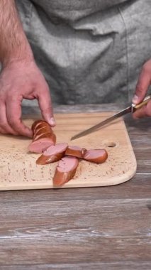 Adam piknik için barbekü sosisi kesiyor. Dışarıdaki lokantada lezzetli bir öğle yemeği. Dikey video