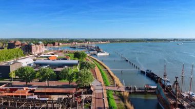 Hollanda, Lelystad 'daki Batavialand Müzesi üzerinde uçuyor. Güzel yeşil göl manzarası ve insansız hava aracı görüntülerinden huzurlu su manzarası..